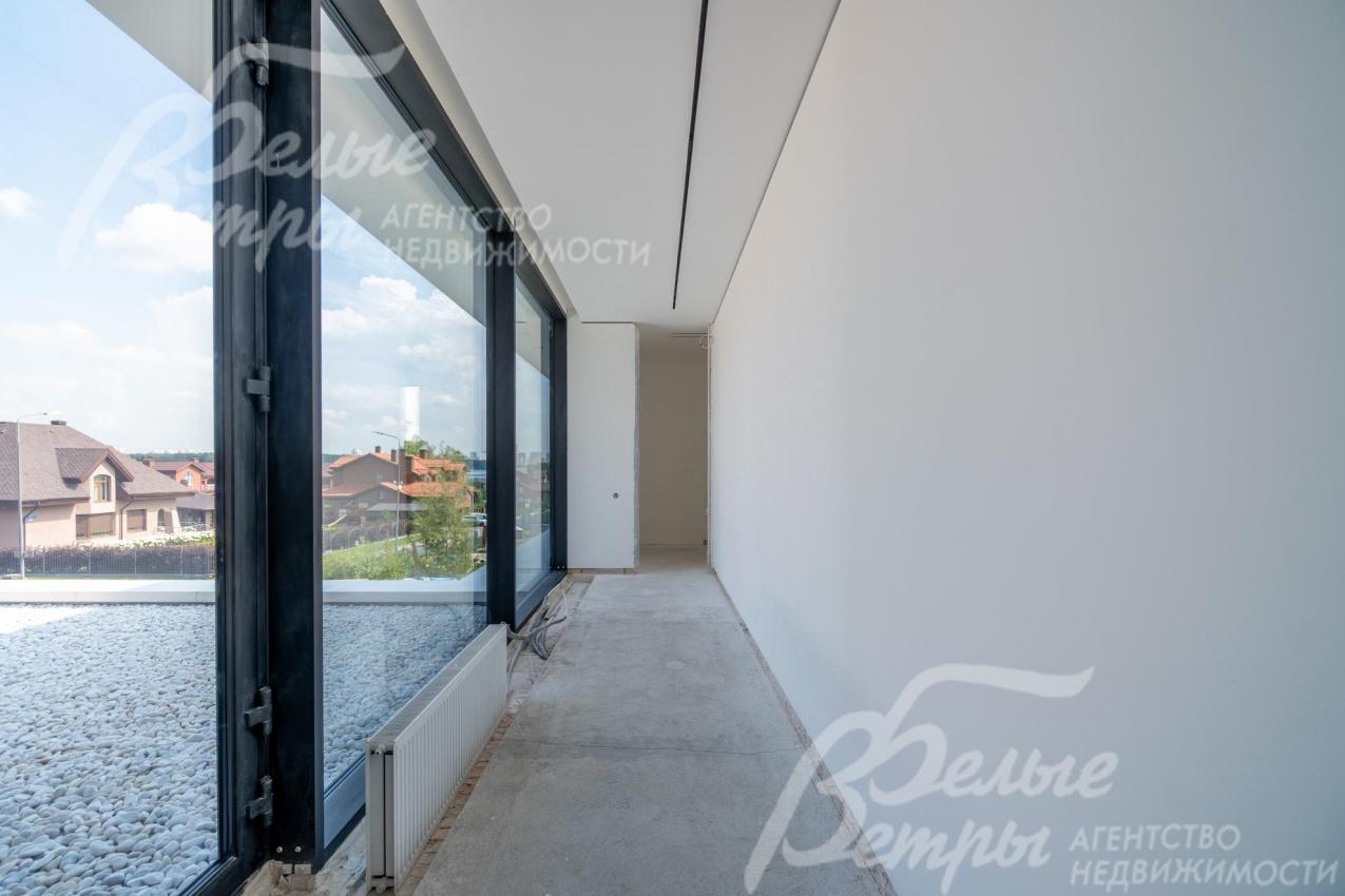 Коридор с панорамным остеклением: из окон открывается вид на участок и коттеджный посёлок