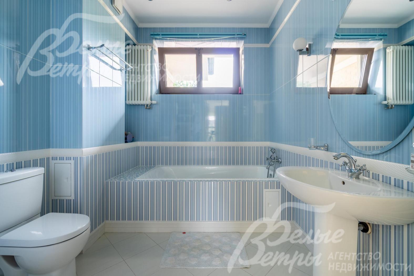 Санузел на втором этаже, оформленный в бело-голубых оттенках, с ванной у окна