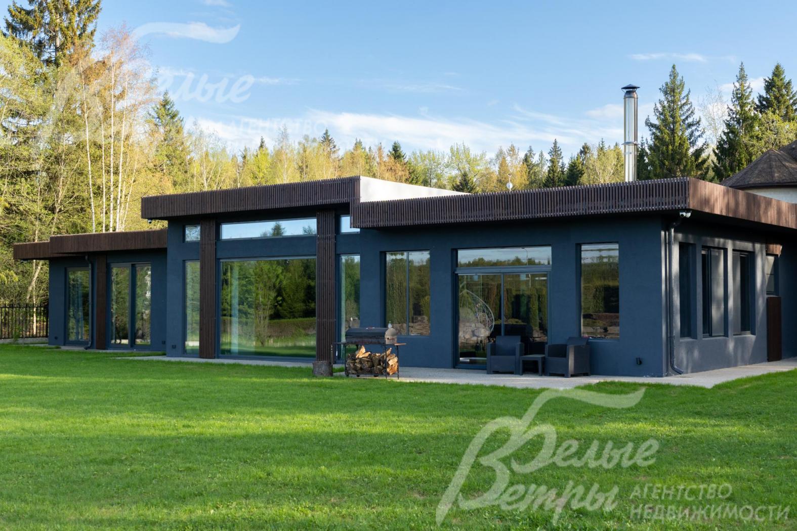 Дом - одноэтажный, с панорамным остеклением, в стиле минимализма. C деревьями и ландшафтом, в окружении леса.