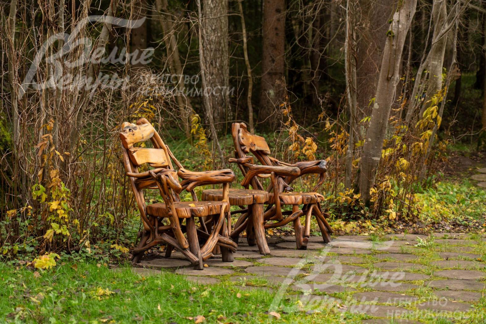 В тени раскидистых деревьев расположились уютные деревянные кресла со столиком