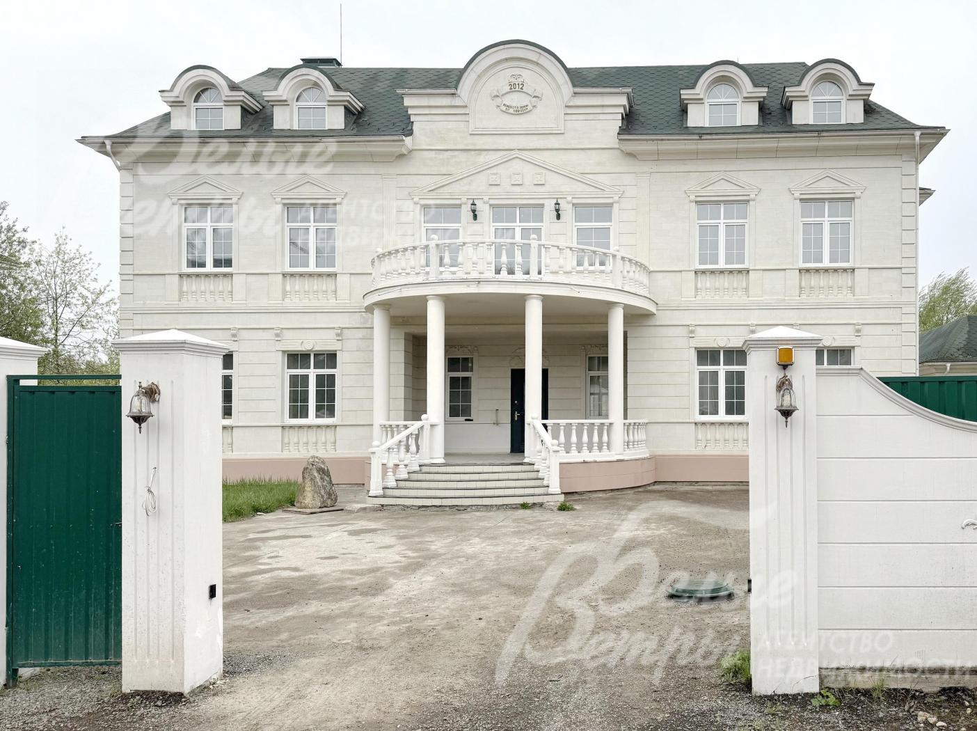 Усадебный ансамбль стоит на огороженном участке: по фасаду - каменный забор, облицованный искусственным камнем в едином стиле со строениями