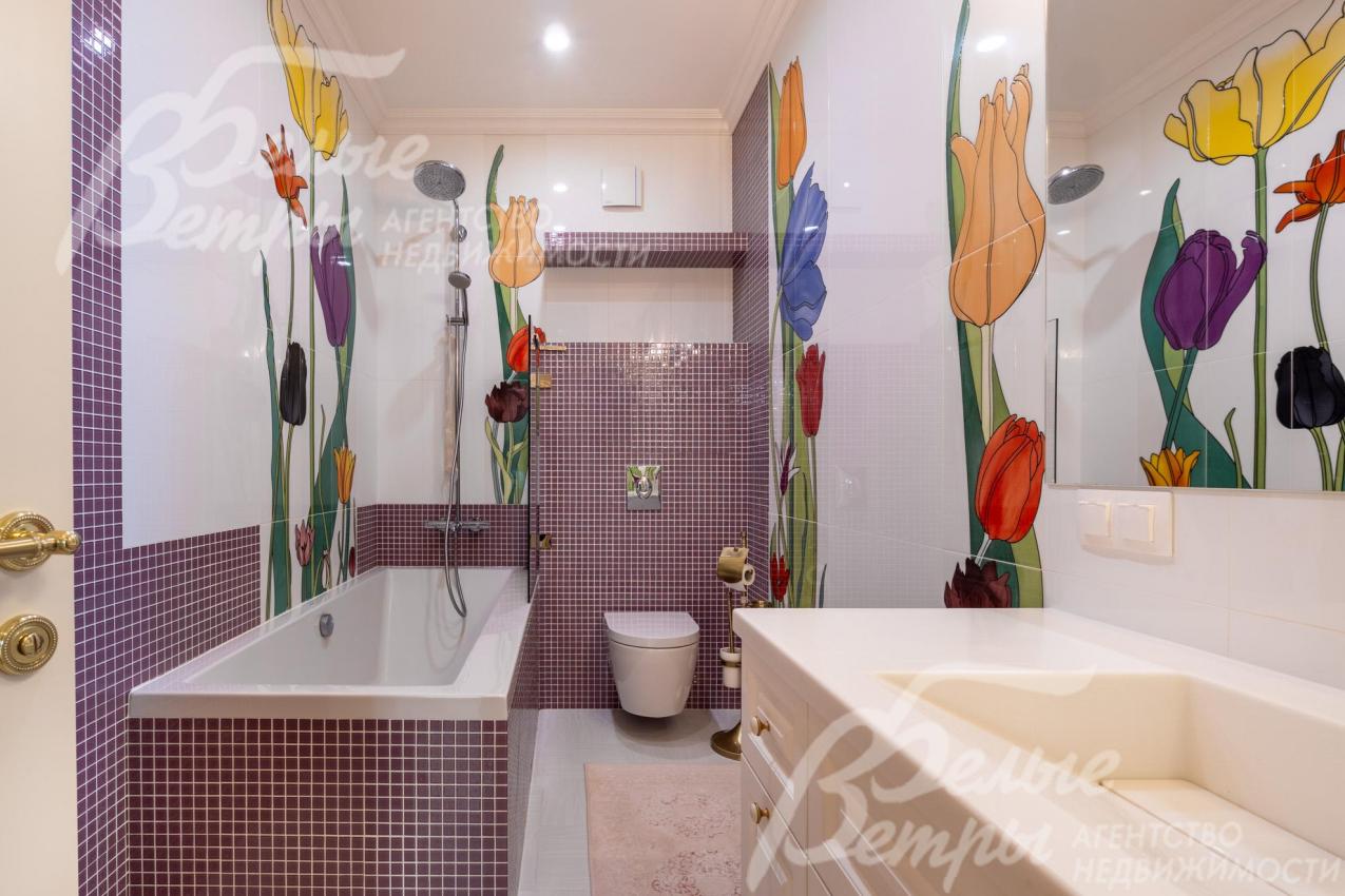 Санузел на втором с ванной с оригинальным дизайнерским оформлением: стены украшены крупными красочными рисунками тюльпанов в насыщенных оттенках