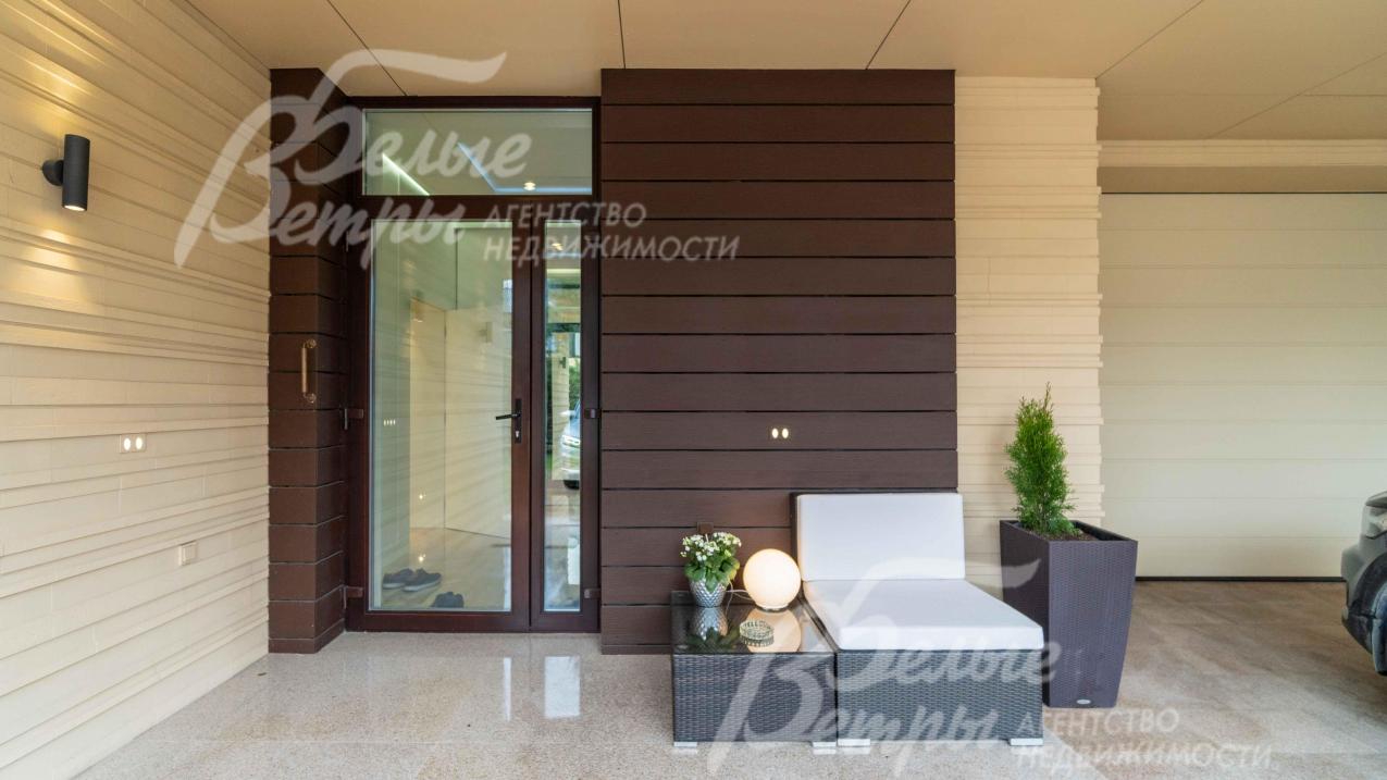 Главный вход в дом со стеклянной дверью, под большим нввесом